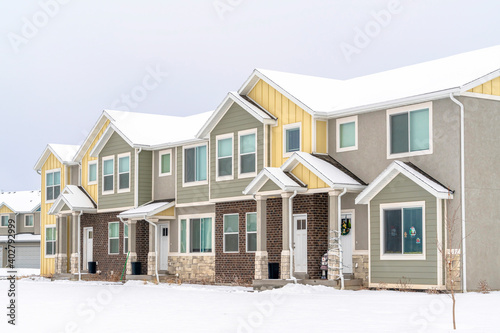 Two storey homes with white doors at front entrances with snowy roofs in winter