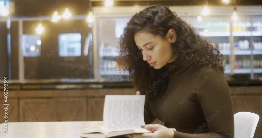 Concentrated Latin female student in library with modern interior and reading literature. intelligent woman interested on book for leaders. Curly hair Brazilian girl. 4K. Concentrated Latin female student in library with modern interior and reading literature. intelligent woman interested on book for leaders. Curly hair Brazilian girl. 4K.