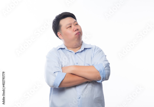 Asian fat man in blue shirt arms crossed and looking to copyspace isolated on white background. © Touchr