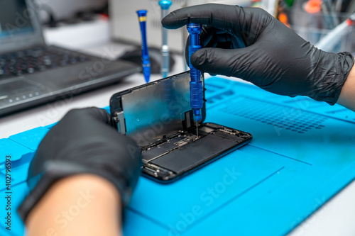 hands of a master disassembling a cell phone with a screwdriver