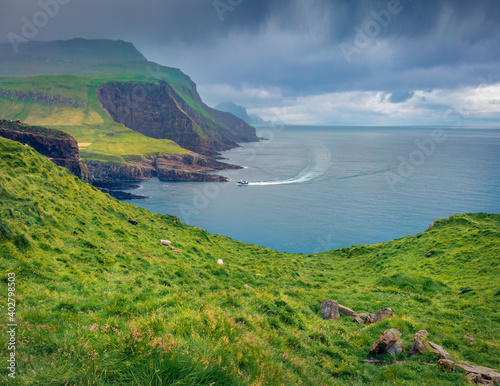 Motorboat excursion in the rainy day on Faroe Islands. Dramatic morning view of Mykines island, Denmark, Europe. Fantastic seascape of Atlantic ocean in August. Beautiful summer scenery..