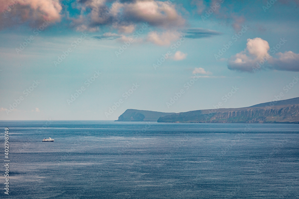 Long focus photography. Small fishing boat on the surface of Atlantic ocean. Beautiful morning scene of  Faroe Islands, Denmark, Europe.