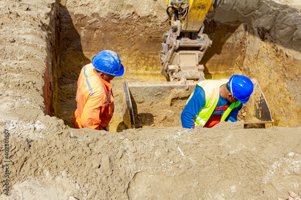 Workers are using shovels to set up right measures in square trench Workers are using shovels to set up right measures in square trench