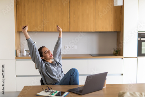 Young pretty woman using computer laptop at kitchen screaming proud and celebrating victory and success