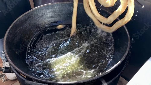 Traditional Spanish sweet pastry churros preparation in big pan. Mobile footage
