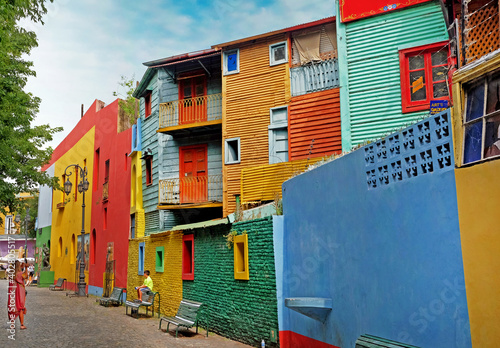 Woman photographing a child in front of colorful buildings of the Argentinean district La Boca, in Buenos Aires, during a summer day with a blue sky. photo