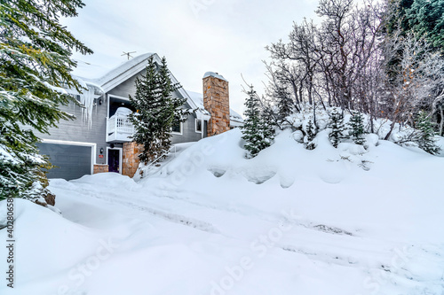 House facade and snowy hill slope against cloudy sky on a winter landscape © Jason