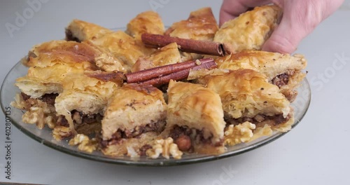Hand picking up a piece of traditional baklava from a plate on white - gray background - studio shot