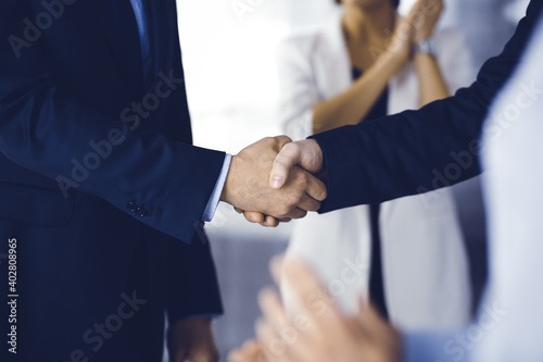 Unknown businesspeople are shaking their hands after signing a contract at meeting, close-up. Business communication concept © cameravit
