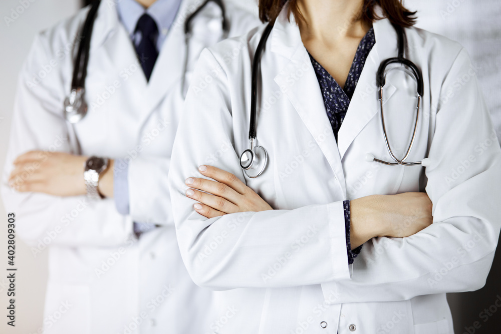 Group of modern doctors standing as a team with arms crossed in sunny hospital and ready to help patients. Medical help, insurance in health care Group of modern doctors standing as a team with arms crossed in sunny hospital and ready to help patients. Medical help, insurance in health care