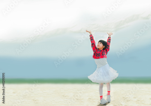 A girl wearing a red dress for a celebration. She was raising her arms up to touch the white canvas over her head that looked like a cloud.