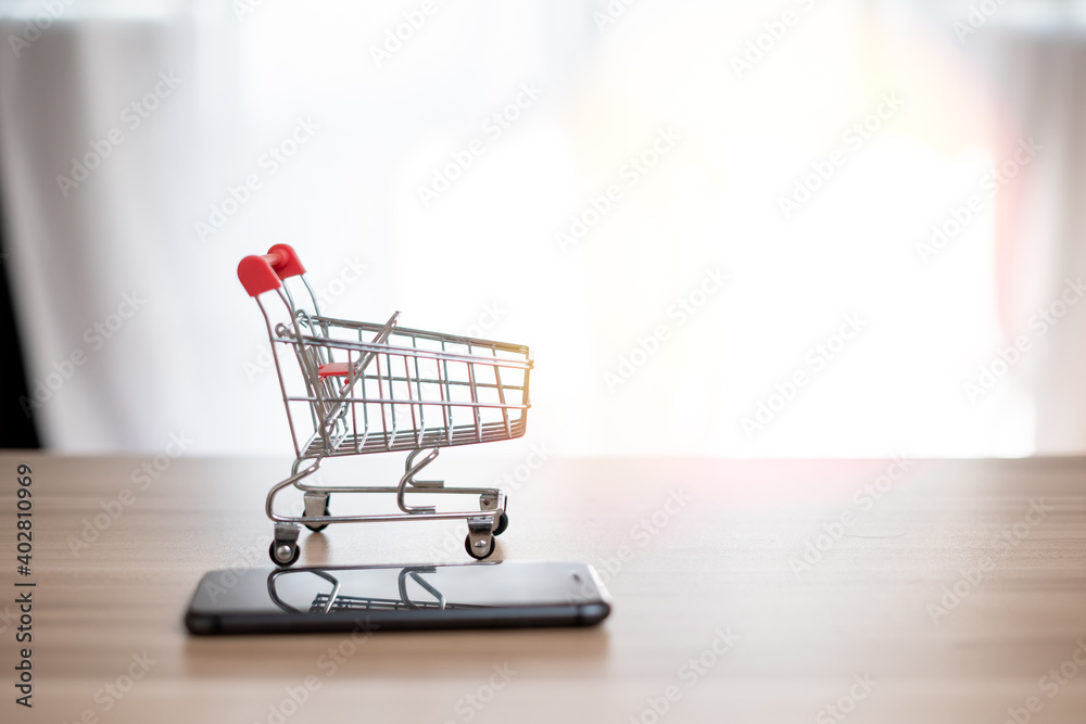 Small carts and smartphones are placed on tables. Trading ideas, shopping online, being at home, selling and buying. Pay anywhere because there is internet that connects people all over the world. Small carts and smartphones are placed on tables. Trading ideas, shopping online, being at home, selling and buying. Pay anywhere because there is internet that connects people all over the world.