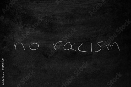 the words "no racism" written on a blackboard