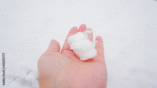 Asian woman holding natural soft white snow outdoors. On a snowy winter day, spend time outdoors touching the cold snow.