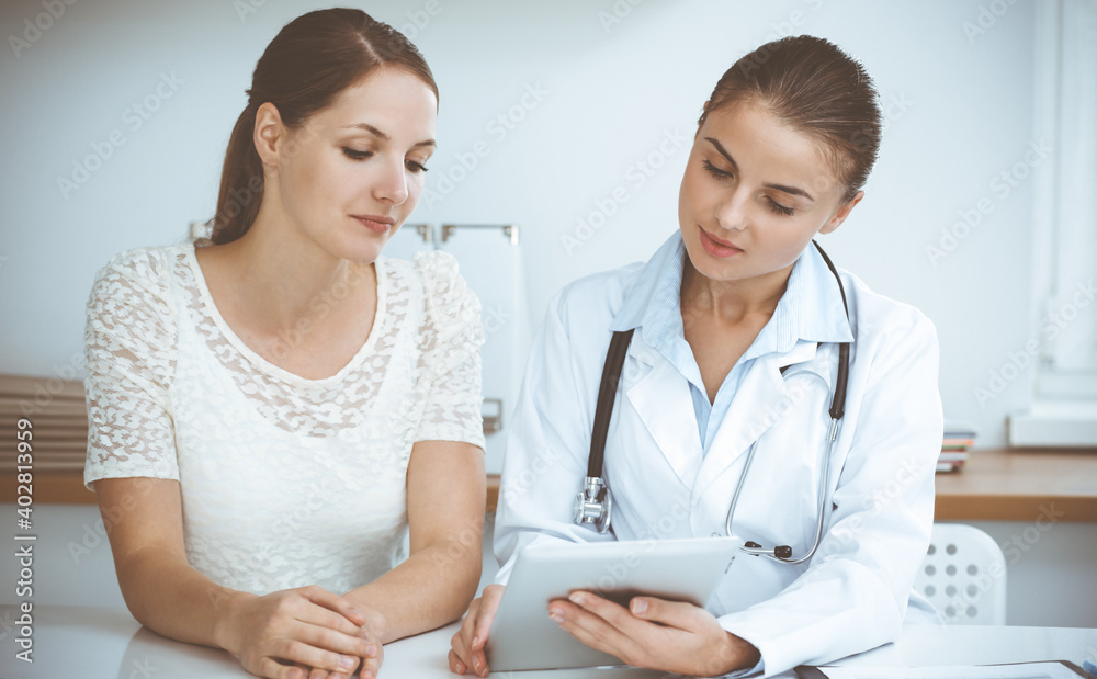 Doctor and patient are sitting and discussing health examination results while using tablet computer. Health care, medicine and good news concepts Doctor and patient are sitting and discussing health examination results while using tablet computer. Health care, medicine and good news concepts