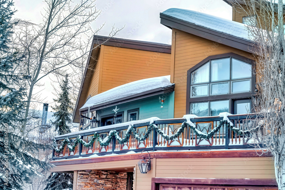 Home facade with half pitched roofs and balcony covered with snow in winter