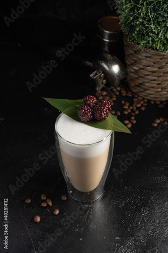 Blackberry latte in a transparent two-layer thermo mug. Hot drink made from coffee or cocoa, with milk foam, blackberries and bamboo leaves. photo