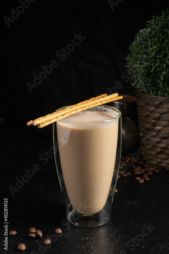 Cocoa with salted straws in a transparent two-layer thermo glass. A hot drink made from coffee or cocoa, with milk, and a decoration from three crunching snack sticks. photo