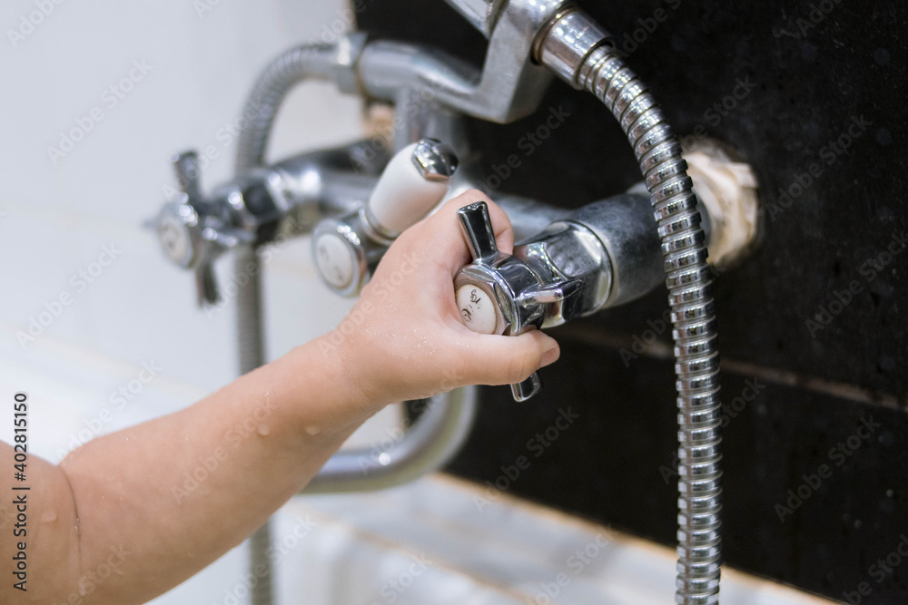 Obraz premium The child turns on the tap in the bathroom. The kid bathes in the bath. The baby washes her hands. Hygiene. Bathroom.