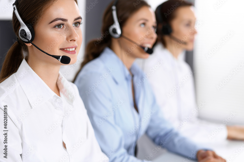 Call center. Group of operators at work. Focus on beautiful business woman in headset Call center. Group of operators at work. Focus on beautiful business woman in headset