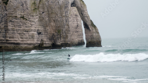 Surfer under the cliff of Etretat, winter