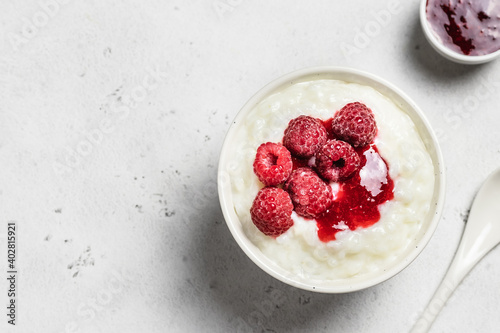 Coconut milk rice pudding in a bowl with frozen raspberry. Top view, space for text. photo