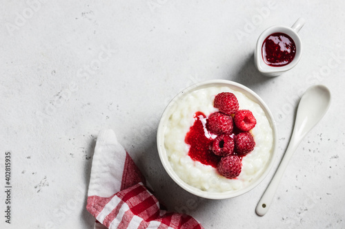 Almond milk rice pudding with raspberry sauce  in a bowl. Top view, space for text.