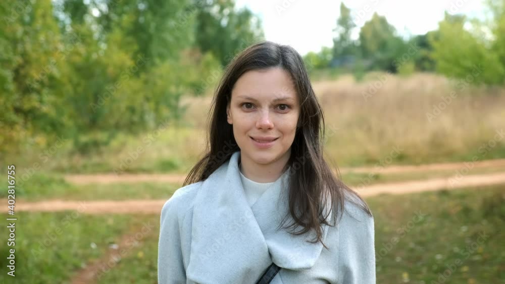 Portrait of young brunette woman in autumn park, she is looking at camera and smiling. Wearing in wool gray coat. Walking in park outdoors. Portrait of young brunette woman in autumn park, she is looking at camera and smiling. Wearing in wool gray coat. Walking in park outdoors.