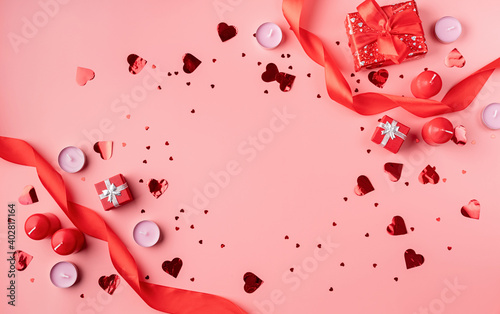 Valentines Day background with candles, gifts, hearts and confetti top view flat lay on pink