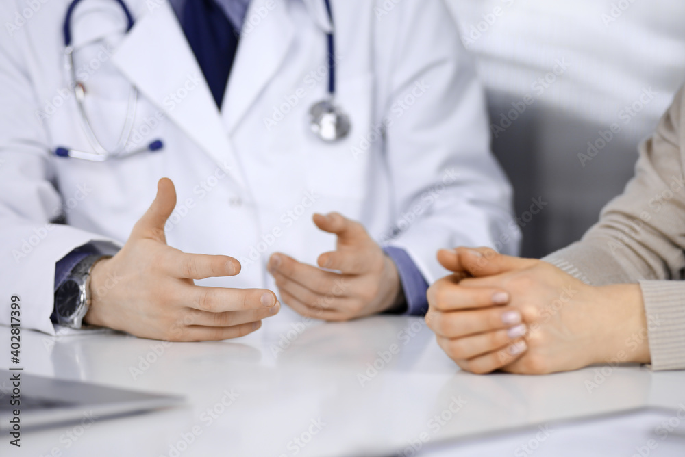 Unknown male doctor and patient woman discussing something while sitting in clinic. Best medical service in hospital, medicine, pandemic stop Unknown male doctor and patient woman discussing something while sitting in clinic. Best medical service in hospital, medicine, pandemic stop