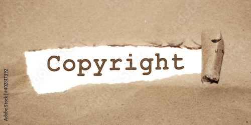 Copyright word uner torn paper. Legal marking of the brand, business concept photo