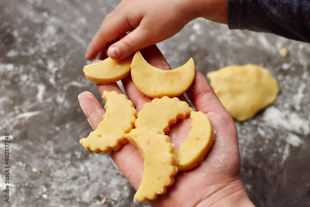 A cute 3-4 year old girl makes her own Christmas cookies. Family vacation at home during the holidays. Flour and dough. New Year's and Christmas. Child holding dough in his hands