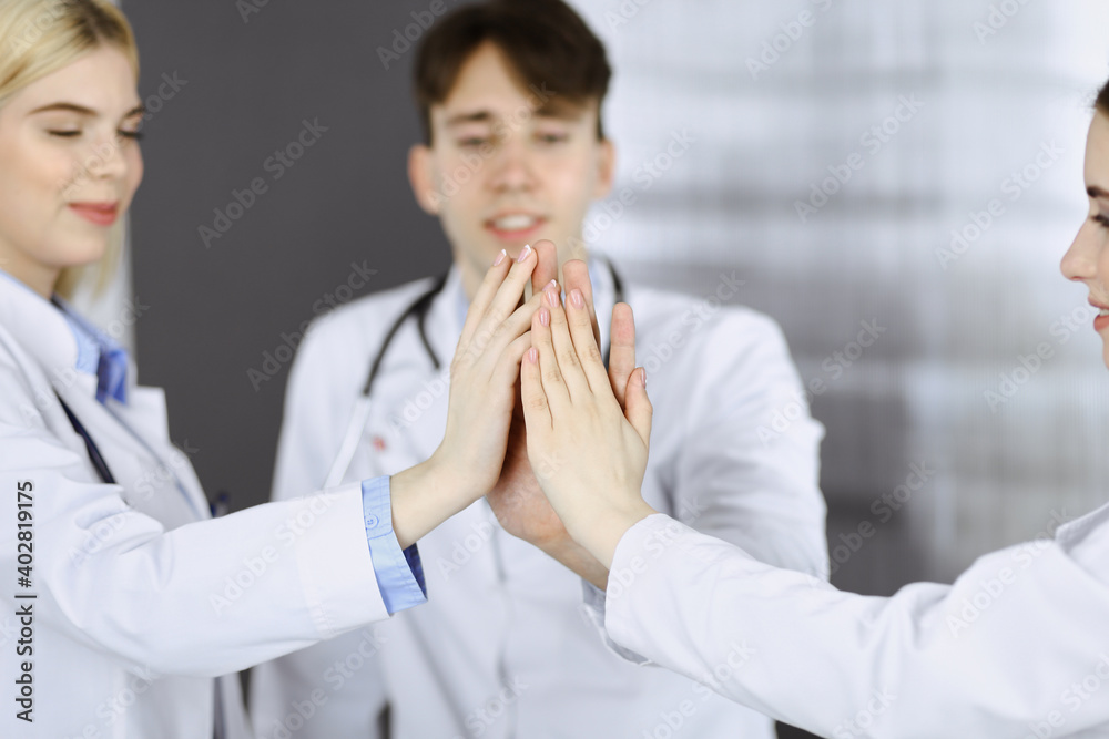 Group of modern doctors are joining hands and giving Five to each other as a sign of strong teamwork and ready to help patients. Coronavirus countering and medicine concept Group of modern doctors are joining hands and giving Five to each other as a sign of strong teamwork and ready to help patients. Coronavirus countering and medicine concept