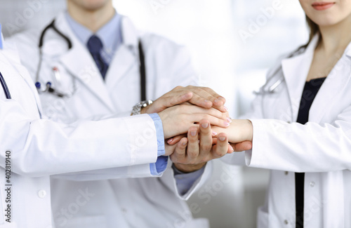 Group of modern doctors joining hands as a circle and ready to help patients. Teamwork in medicine, Coronavirus countering concept © rogerphoto