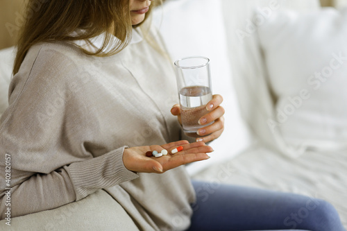 Close-up woman holding pills time to take medications, cure for headache, high blood pressure pain killer drugs at home. Stay at home concept during Coronavirus pandemic