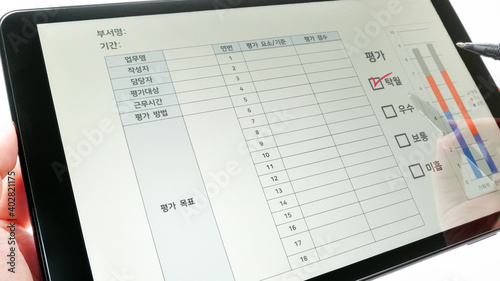 Work performance appraisal (evaluation) is reported on the tablet PC. Employment concept. Translation:Department, Period, Task, Draftsman, Manager, Evaluation Subject, Factor, Score, Rating categories