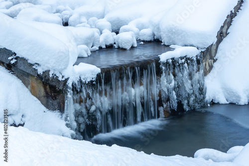 Tranquil mountain creek waterfall surrounded by a frozen landscape in the Austrian alps (Filzmoos, Salzburg county)