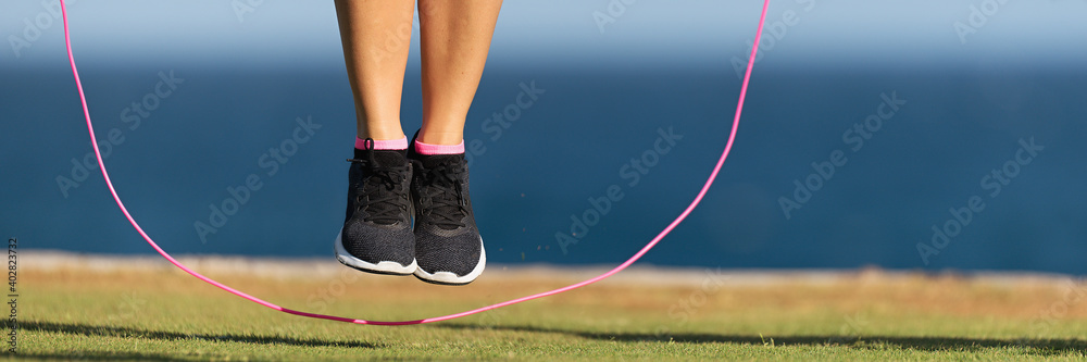 Young fitness woman warming up with jump rope outdoors - obrazy, fototapety, plakaty 