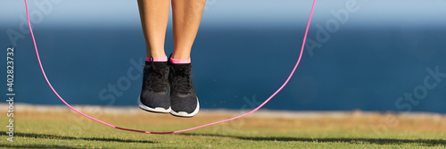 Young fitness woman warming up with jump rope outdoors photo
