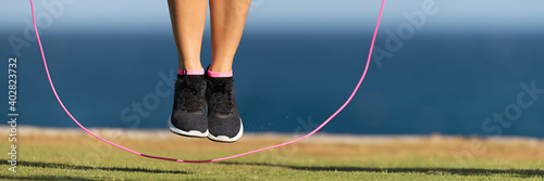 Young fitness woman warming up with jump rope outdoors