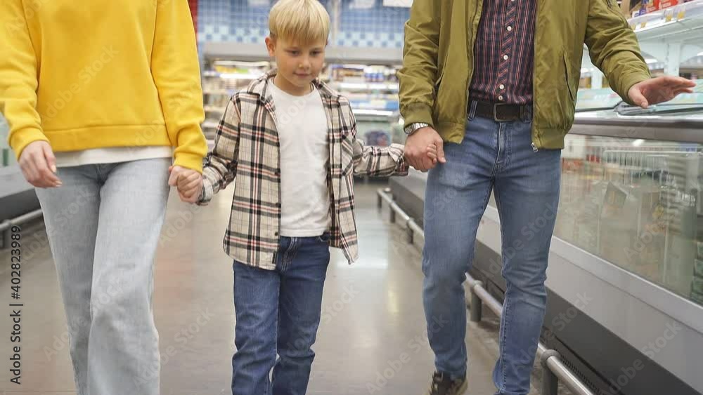 family walk in the supermarket, caucasian parents holding hands of their son, enjoy shopping family walk in the supermarket, caucasian parents holding hands of their son, enjoy shopping
