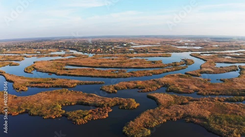 Top view of the beautiful Samarskie Plavni on the Dnieper with a village nearby in the warm evening light. Aerial UHD 4K drone realtime video, shot in 10bit HLG and colorized