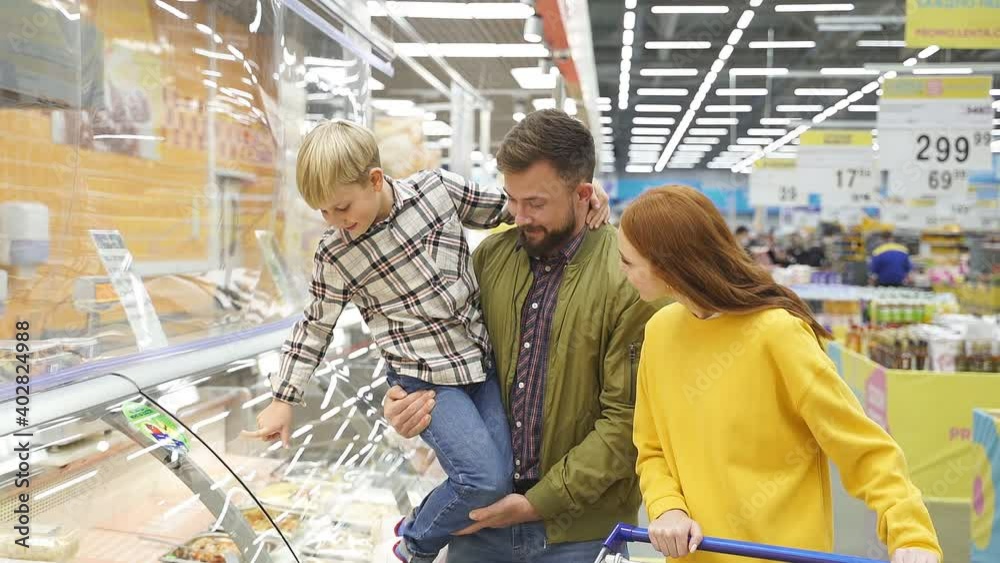 Son show something delicious to parents in store, he wants parents to buy it, point finger. Son show something delicious to parents in store, he wants parents to buy it, point finger.