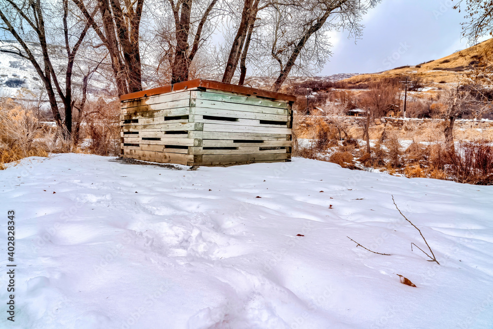 Wooden storage shed with rusty metal roof on snow covered landscape in winter Wooden storage shed with rusty metal roof on snow covered landscape in winter