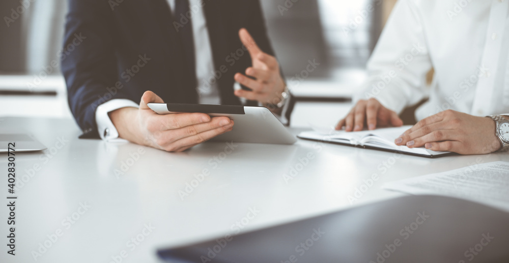 Unknown business people using tablet computer in modern office. Businessman or male entrepreneur is working with his colleague at the desk Unknown business people using tablet computer in modern office. Businessman or male entrepreneur is working with his colleague at the desk
