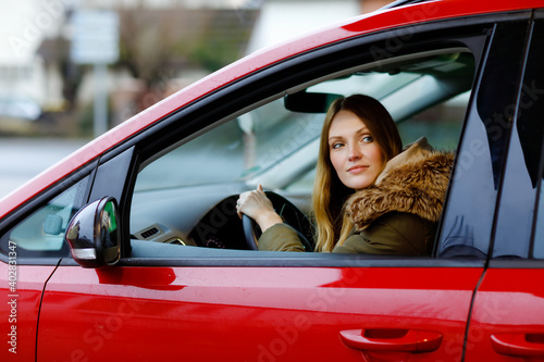 Young attractive woman with happy positive expression, being satisfied with unforgettable journey by car, sits on driver seat. People, driving, transport concept. Winter ski holiday by car
