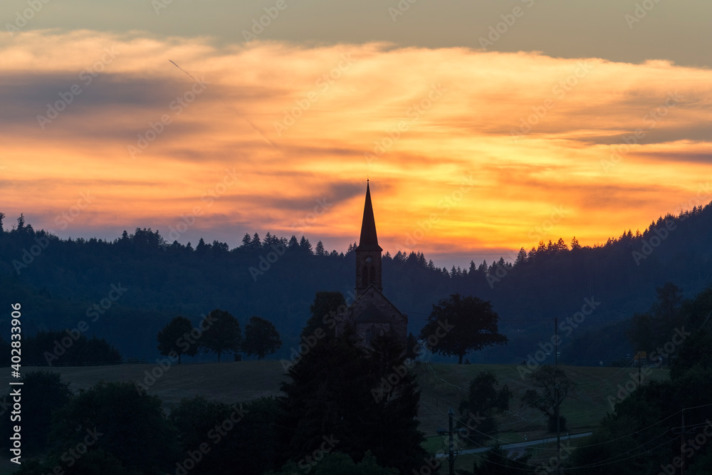 Fototapeta premium Sunset over the village Hofen in the Black Forest with the silhouette of the church