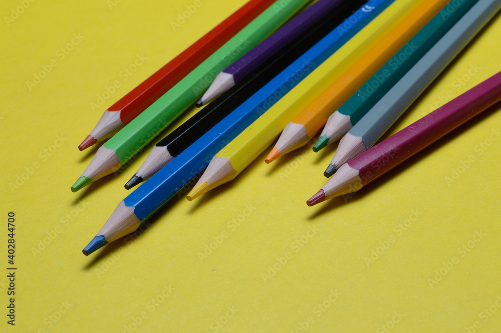 several multi-colored pencils lie on the yellow surface. several multi-colored pencils lie on the yellow surface.
