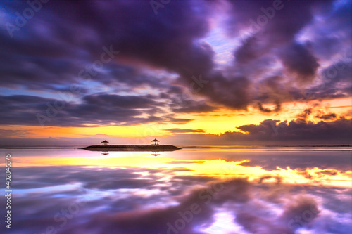 Beautiful sunrise on Bali in Sanur by the sea with a view over the beach to the sea. a temple and breakwater in the sea at sunrise. Hinuistic