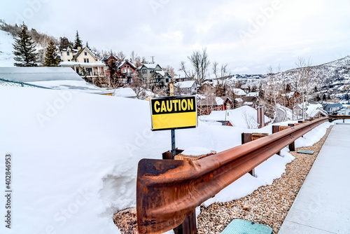 Caution sign on the rusty guardrail of a road in the snowy mountain in winter